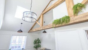 Een kamer met zichtbare houten balken, een hanglamp en groene planten.