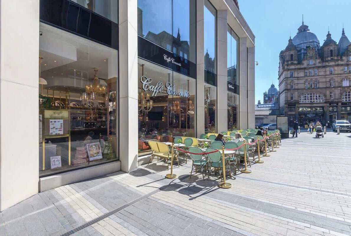 A cafe with outdoor seating and a view of a historic building in the background.