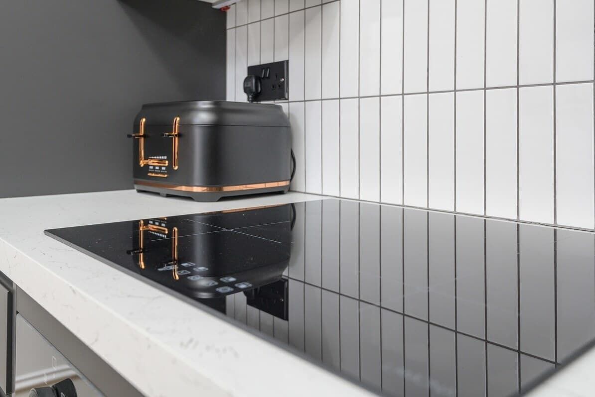 A kitchen with a black induction cooktop and a black toaster.