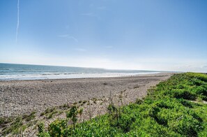 A beach with pebbles and greenery, a clear sky, and the ocean in the background. - Beachfront Thatched Cottage in West Wittering – Sleeps 8, Garden, Parking, Pets (West Wittering)