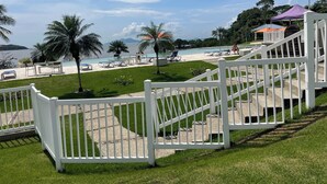 Ein Poolbereich mit weißem Zaun, Palmen und Blick auf das Meer.