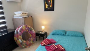 Ein Schlafzimmer mit einem Bett, Kissen, einer Lampe, einem Mülleimer und einem bunten Luftballon.