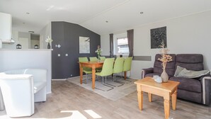 Ein modernes Wohnzimmer mit Essbereich, einer Couch, einem Couchtisch und einem Sessel.