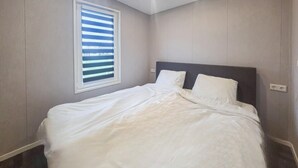 A bedroom with a bed, a window with blinds, and a wall socket. - 2 bedroom cozy home in Den Oever (Den Oever)