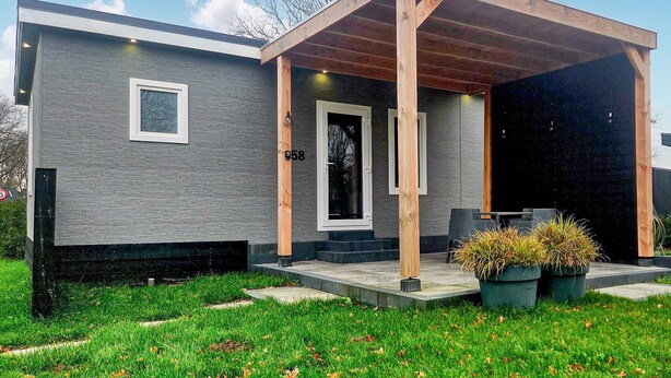 A modern two-story house with a covered porch, a visible door number, and a small outdoor seating area with potted plants. - 2 bedroom cozy home in Den Oever (Den Oever)