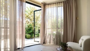 A room with a sofa, a small round table with a plant, and sheer curtains. - Charm & Modern Comfort in East Launceston (East Launceston)