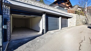 Een gebouw met twee verdiepingen, een garage-ingang, stenen muren en een houten balkon.