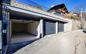 A two-story building with a garage entrance, stone walls, and a wooden balcony. - Residenza panoramica 2 (Ponte di Legno)