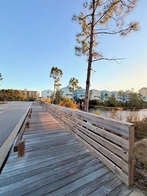 Une promenade en bois qui mène à un quartier résidentiel, avec des maisons et un ciel dégagé.