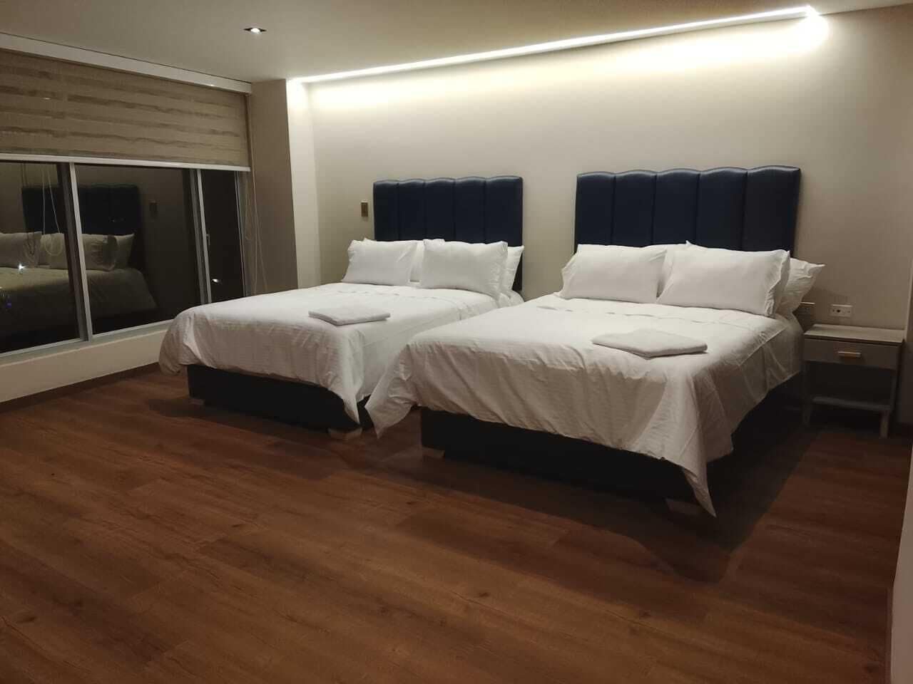 Hotellihuone, jossa on kaksi sänkyä, suuri ikkuna ja puulattia.