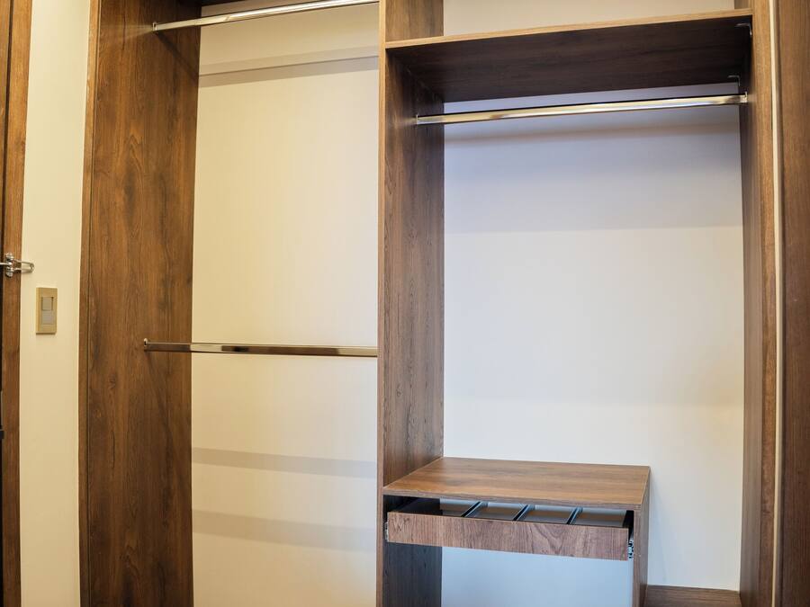 A walk-in closet with wooden shelving and a bench.