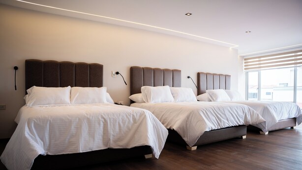 Une chambre d’hôtel avec deux lits, un design moderne et une grande fenêtre laissant entrer la lumière naturelle.