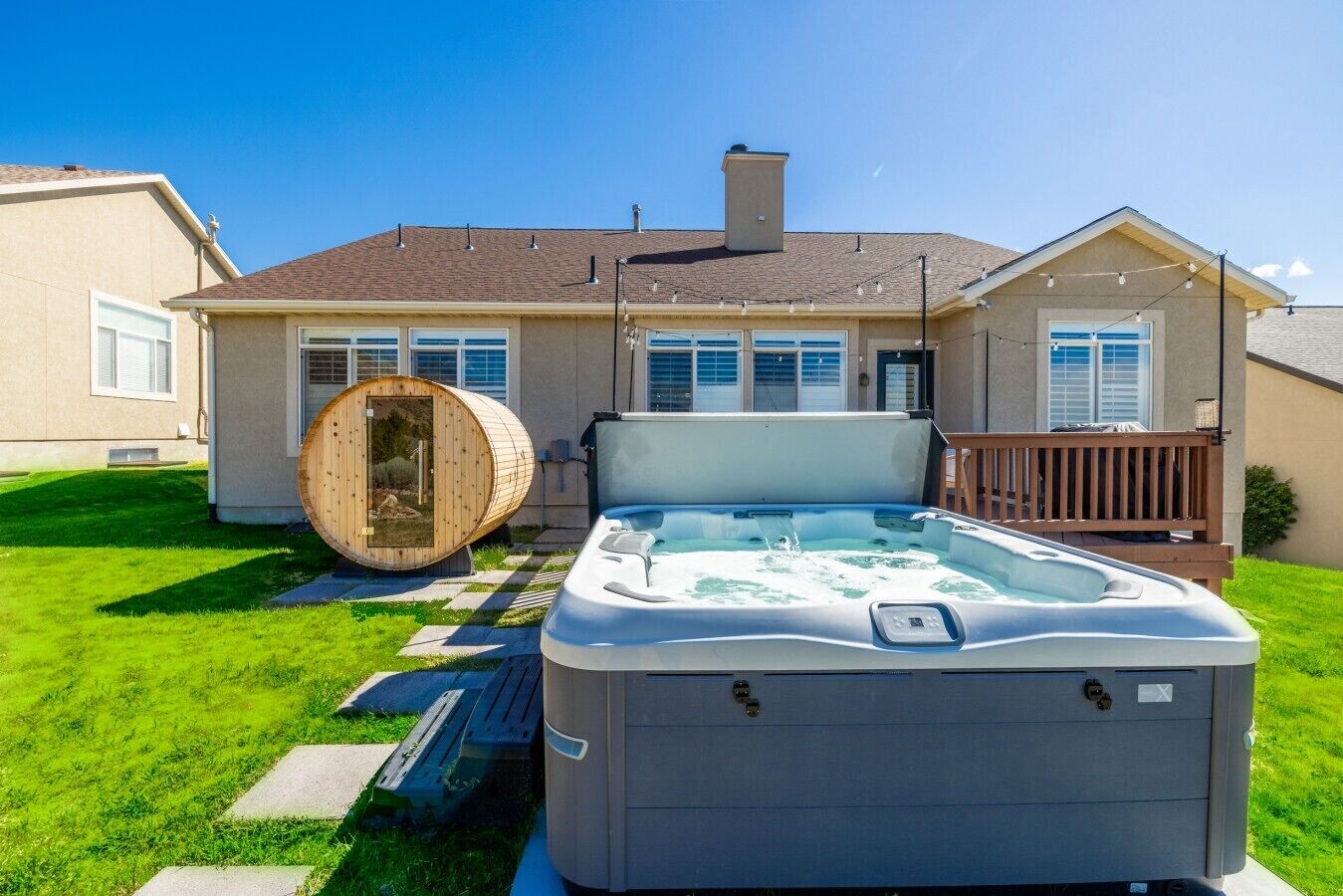 Une maison avec un jacuzzi et un sauna dans le jardin.