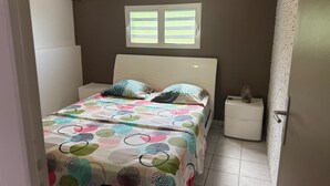 Een slaapkamer met een bed, een nachtkastje, een raam en een wandairconditioner.