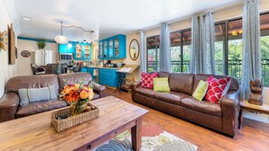 A spacious living area with a brown leather sofa, a wooden coffee table, and a kitchen in the background. - Redwood Loft - 2 Minutes from Sequoia National Park (Three Rivers)