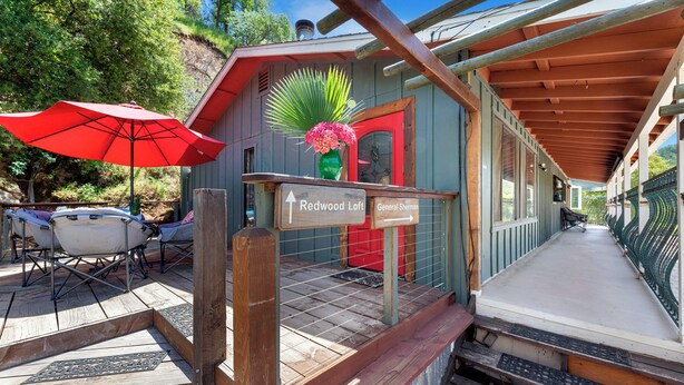A rustic cabin with a red door, a sign pointing to the Redwood Loft, and a red umbrella. - Redwood Loft - 2 Minutes from Sequoia National Park (Three Rivers)