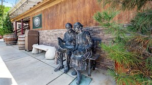 A wooden building with a stone wall and a bench with a statue of two figures. - Redwood Loft - 2 Minutes from Sequoia National Park (Three Rivers)