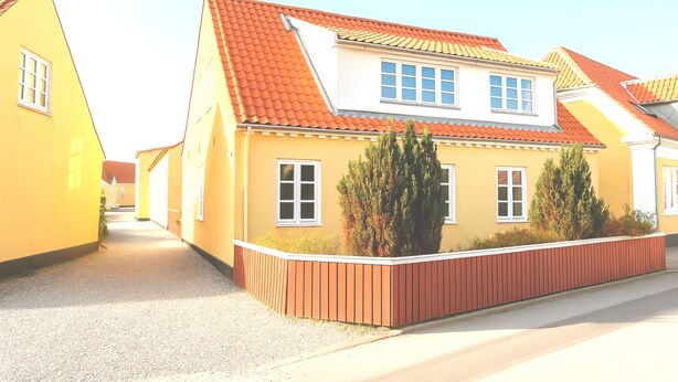 A yellow two-story house with a red-tiled roof, white windows, and a gravel driveway. - GBH - Central Skagen Townhouse (Skagen)