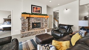 A living room with a stone fireplace, leather furniture, and a ceiling fan. - Eden Mountain View Retreat: Pool, Hot Tub, Fireplace (Eden)
