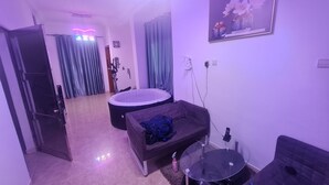 A room with a bed, a small couch, a round table, and a wall-mounted TV.