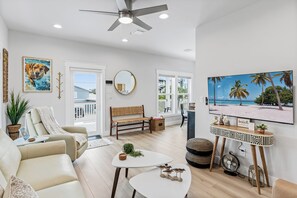A modern living room with a sofa, coffee table, and a TV on a stand. - Salty Sunrise - Private Heated Pool Paradise In IRB Only Minutes To The Beach w/ Golf Cart (Indian Rocks Beach)