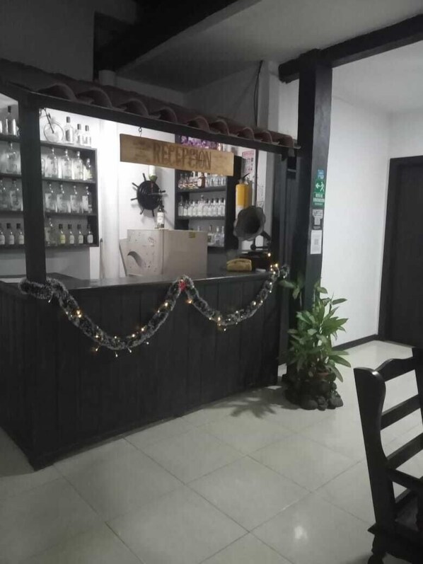 Un espace d’accueil comprenant un comptoir, des étagères remplies de bouteilles, une enseigne au-dessus du comptoir et une chaise.