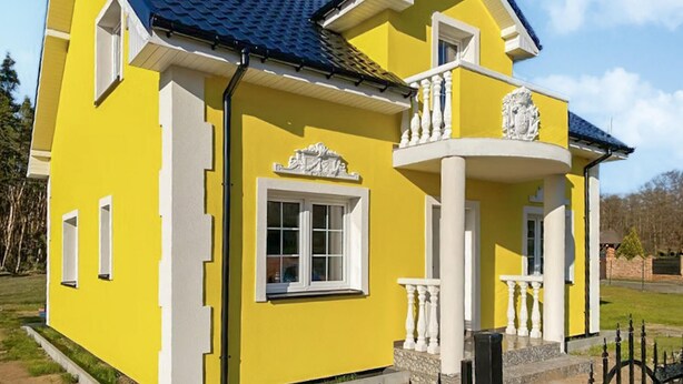 A yellow building with a blue roof, white window frames, and a balcony with white balustrades. - Awesome home in Nowe Warpno with WiFi (Nowe Warpno)