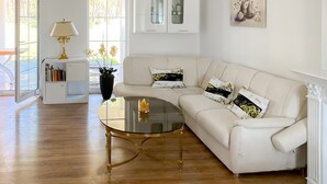 Una sala de estar moderna con una mesa de centro de vidrio, un sofá blanco y una estantería.