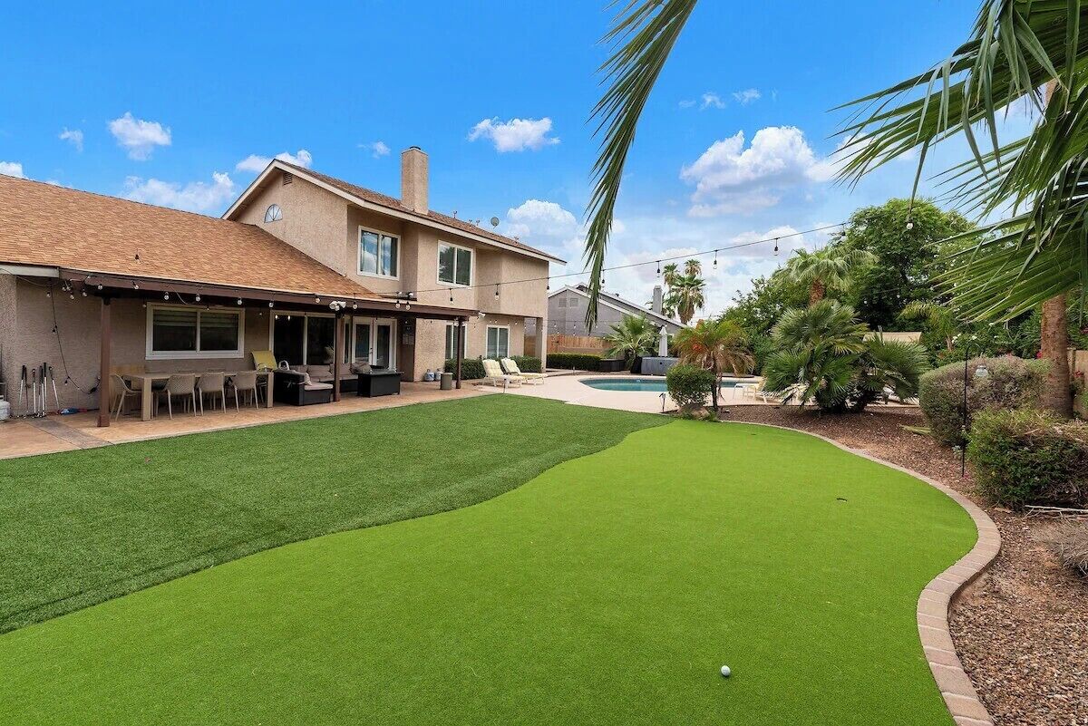 A house with a backyard containing a lawn and a swimming pool.
