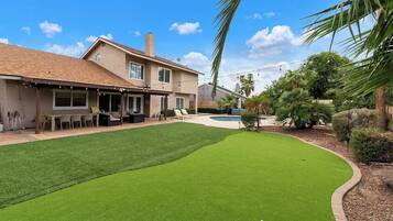 A house with a backyard containing a lawn and a swimming pool.