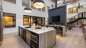 Een moderne keuken met een groot eiland, inbouwapparatuur en hanglampen.