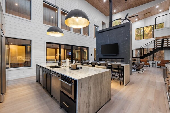 A modern kitchen with a large island, built-in appliances, and pendant lighting. - Luxury Cabin w/ Golf Sim & Pickleball Court (Broken Bow)