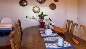 A wooden dining table with a crocheted placemat, a potted plant, a vase with flowers, and a traditional stringed instrument. - 2 bedroom gorgeous home in Borgholm (Borgholm)