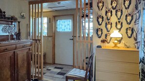 A room with a wooden cabinet, a chair, a lamp, and wall-mounted animal skulls. - 2 bedroom gorgeous home in Borgholm (Borgholm)