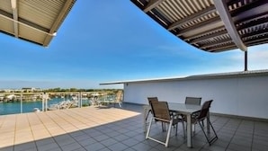 Terraço com mesa e cadeiras com vista para um porto de iates.