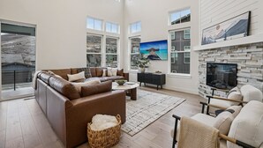 Ein geräumiges Wohnzimmer mit einem braunen Ledersofa, einem Couchtisch und einem an einer Steinwand befestigten Fernseher.