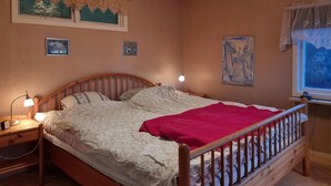A bedroom with a wooden bed, two bedside tables, a nightstand, a window with a view, and wall art. - Lovely home in Ljungskile with WiFi (Ljungskile)