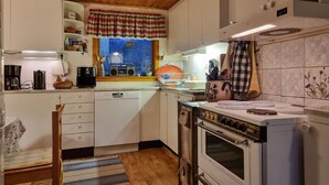 A compact kitchen with white cabinets, a vintage stove, and a window with a plaid curtain. - Lovely home in Ljungskile with WiFi (Ljungskile)