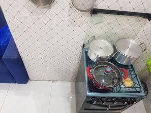 A kitchen with a gas stove, pots, and a strainer. - STUDIO HAPPY HOME (Dakar)