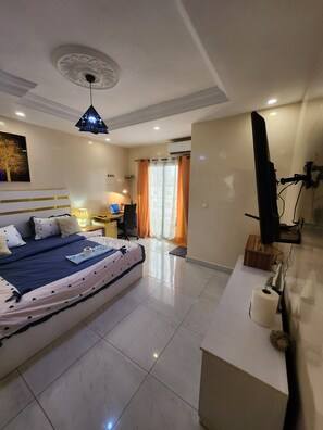 Ein Schlafzimmer mit Bett, Nachttisch, Lampe und Fernseher.