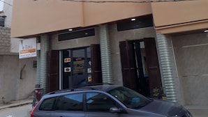 Un immeuble à plusieurs étages, doté d’une façade beige, de nombreuses fenêtres et d’une voiture garée devant.