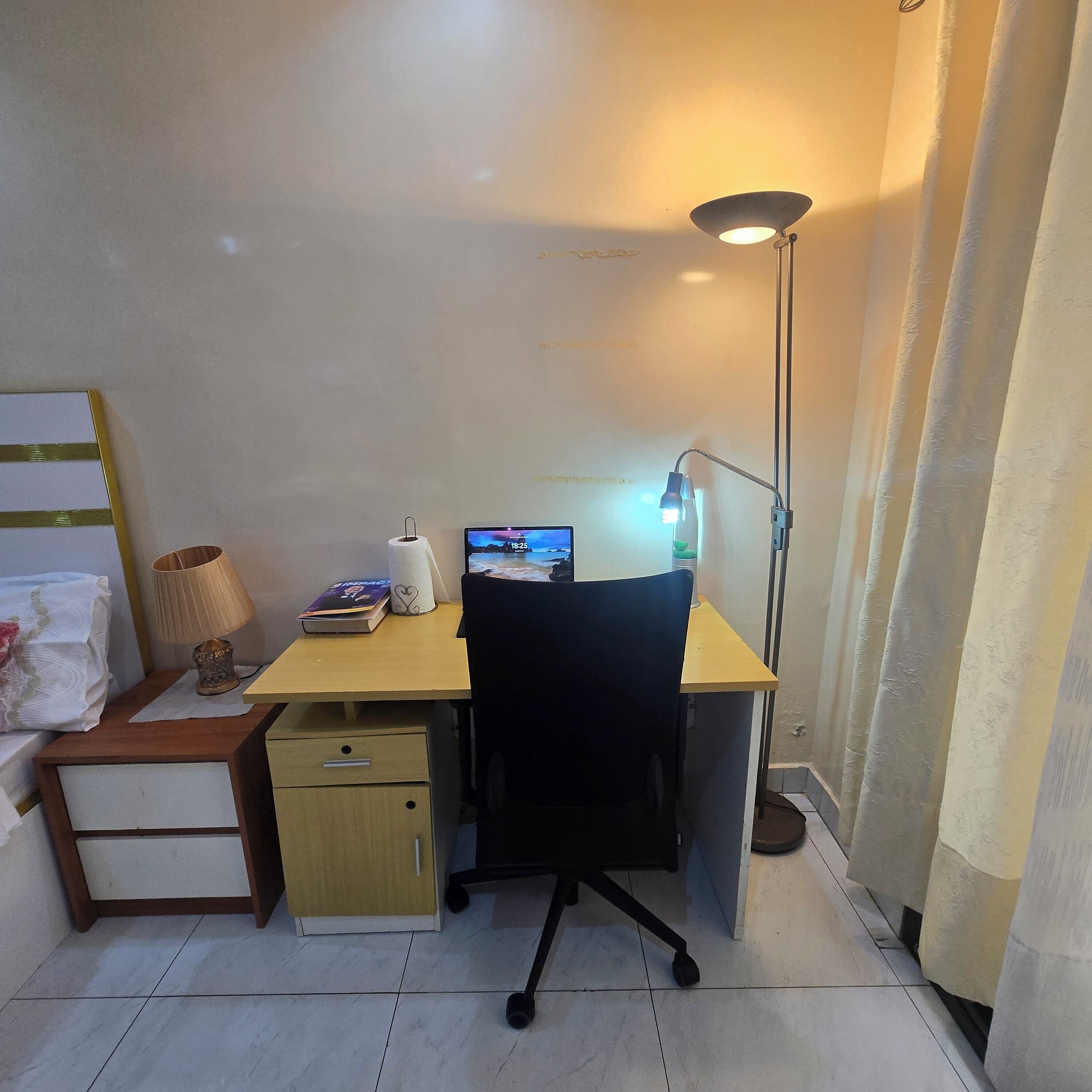 A small office space with a desk, chair, lamp, and a computer monitor.