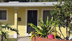 Un bâtiment jaune avec une porte noire, une fenêtre et une boîte aux lettres.