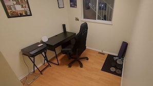 Un petit bureau comprenant un bureau, une chaise et une fenêtre.