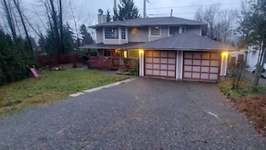 Une maison à deux étages avec un garage, une véranda et une allée menant au garage.