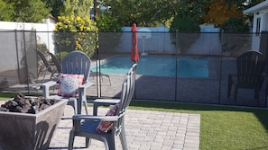 A backyard with a pool, patio chairs, and a red umbrella. - Walk to Old Town - Scottsdale Home with Pool (Scottsdale)