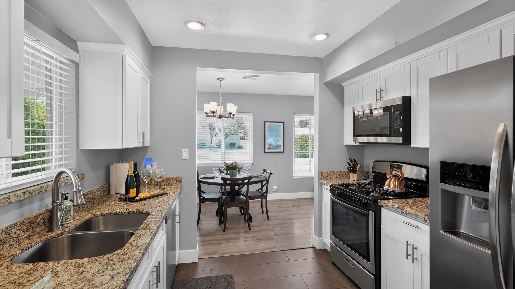 A modern kitchen with granite countertops, stainless steel appliances, and a dining area with a table and chairs.