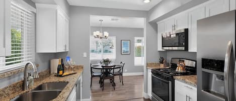 A modern kitchen with granite countertops, stainless steel appliances, and a dining area with a table and chairs.