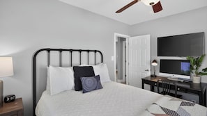 A bedroom with a bed, bedside table, lamp, and a desk with a computer. - Walk to Old Town - Scottsdale Home with Pool (Scottsdale)