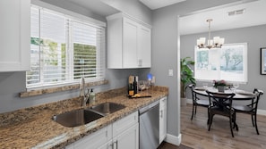 A kitchen with granite countertops, stainless steel appliances, and a dining area with a table and chairs. - Walk to Old Town - Scottsdale Home with Pool (Scottsdale)
